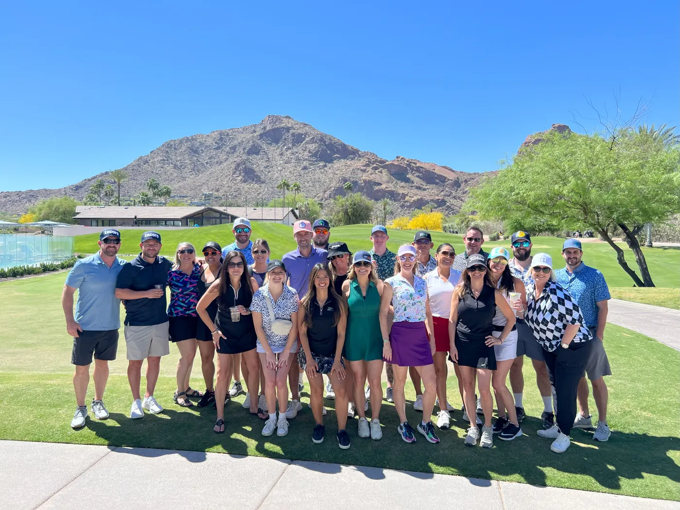 Large group of golfers on the lawn at the Encore Invitational, with a desert mountain behind them