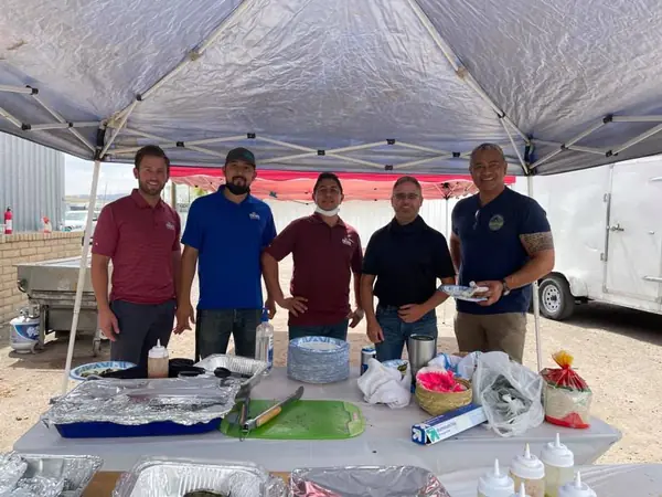 Encore managers serving food under a canopy at a crew cookout