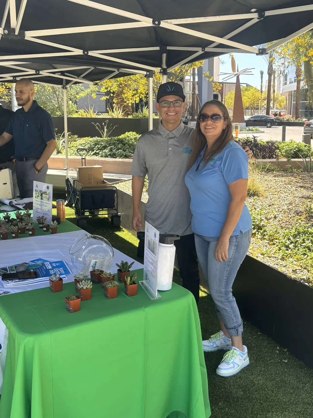 Two Encore team members at an outdoor Earth Day table with small potted plants