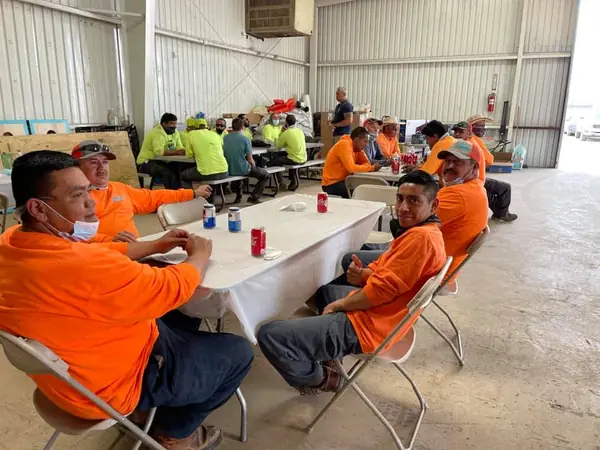 Crew members in orange shirts sharing a meal at tables inside the shop