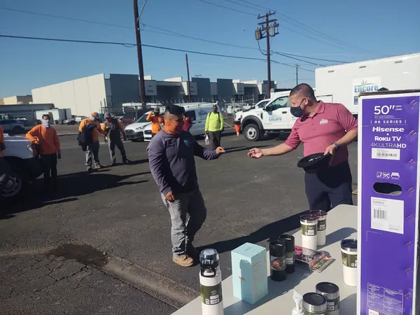 Crew members at an outdoor employee event with prize giveaways, including a television
