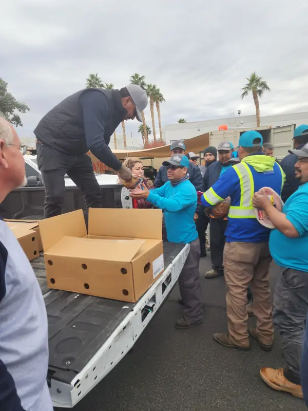 Encore managers handing out holiday hams to crew members from the back of a truck