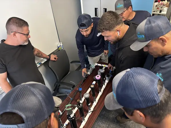 Technicians gathered around an irrigation training board during a hands-on session