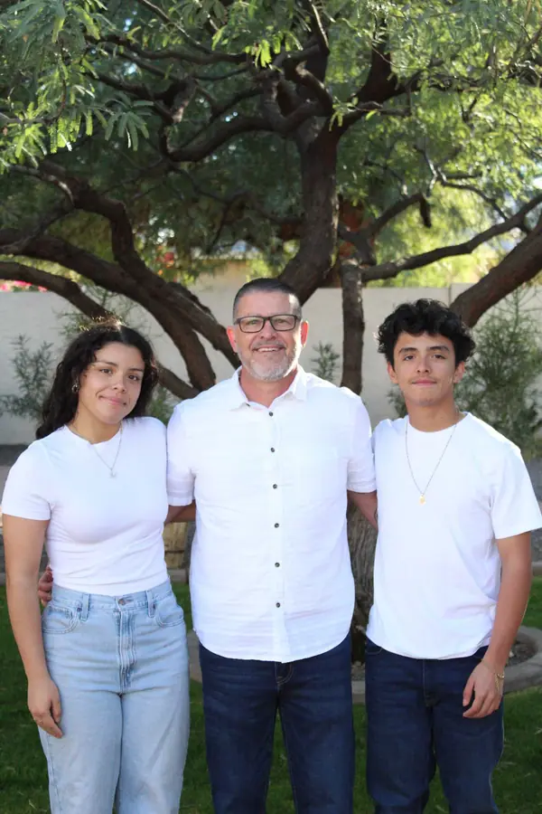 Partner Juan Hernandez standing with two family members under a tree