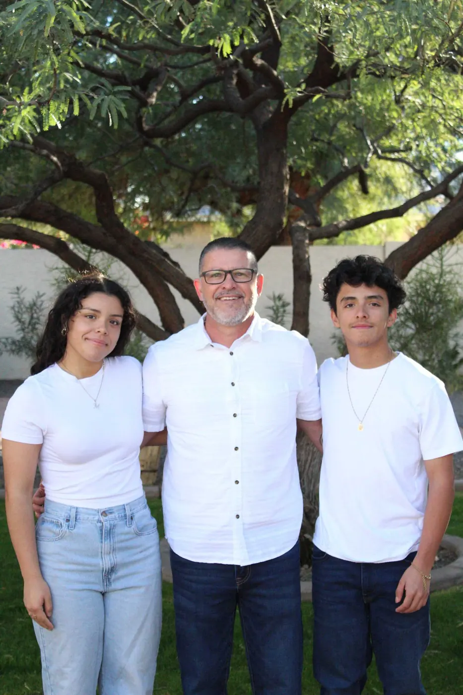 Partner Juan Hernandez standing with two family members under a tree