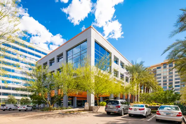 Palo verde trees and desert planting along the parking lot of a white office building at Anchor Centre, Phoenix