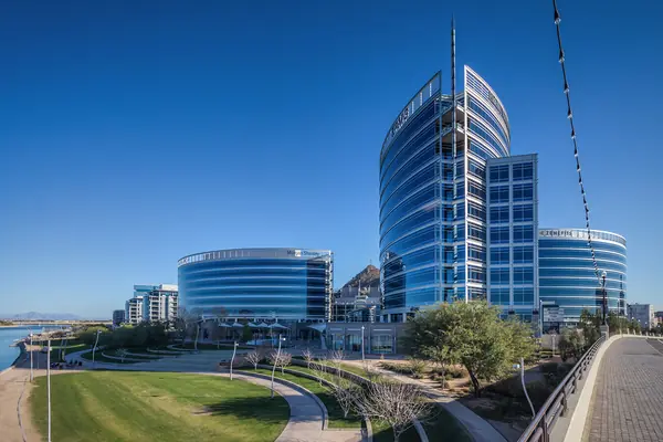 Curving glass towers of Hayden Ferry Lakeside, Tempe, above a lawn and desert-landscaped walkway by the lake