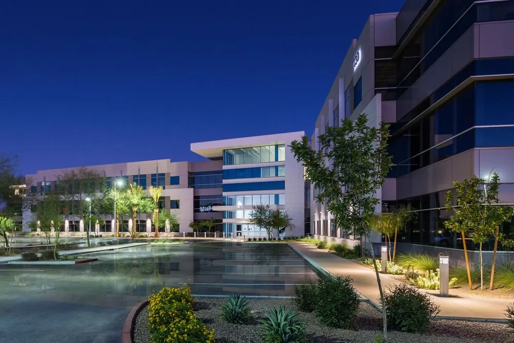 Reflecting pool and lit shrub beds in front of the Waypoint office buildings at dusk