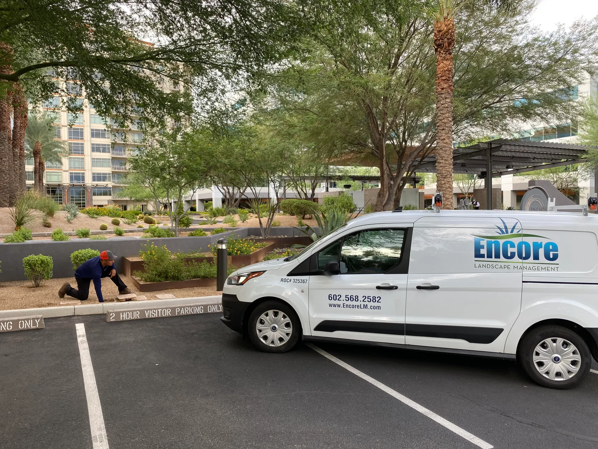 Encore Landscape Management van parked at a landscaped office campus while a technician works on irrigation