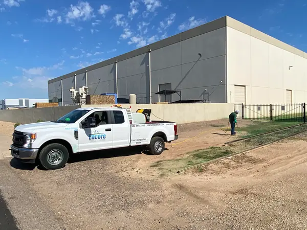 Encore pickup truck at a commercial building while a technician applies a spray treatment