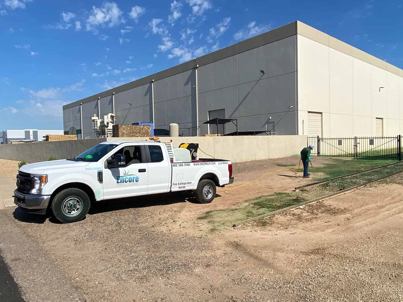 Encore pickup truck at a commercial building while a technician applies a spray treatment